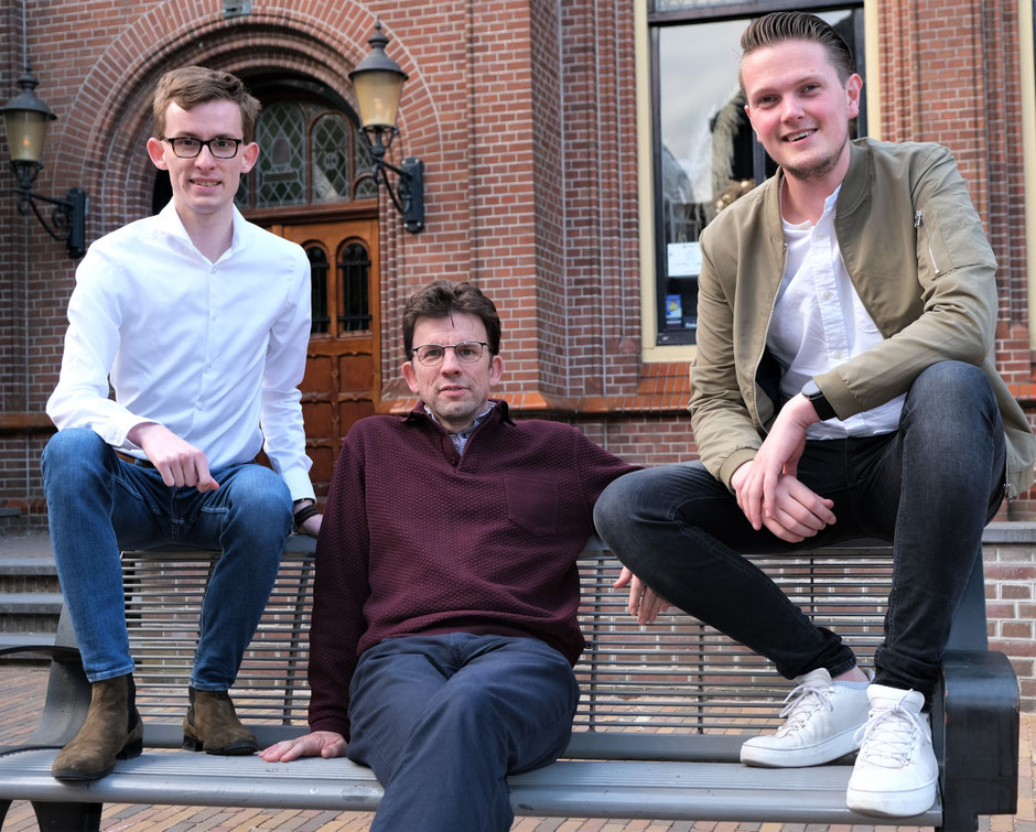 Jarne, Peter en Gerben zitten op een bankje, Jarne en Gerben op de leuning en Peter in het midden op de zitting.