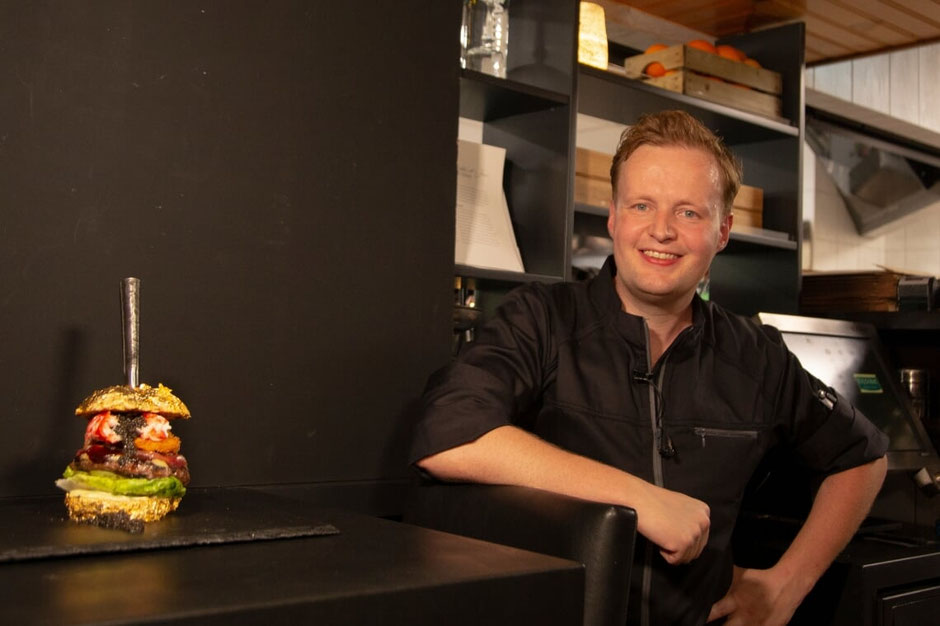 Robbert Jan de Veen poseert bij een bar waar een hamburger op staat